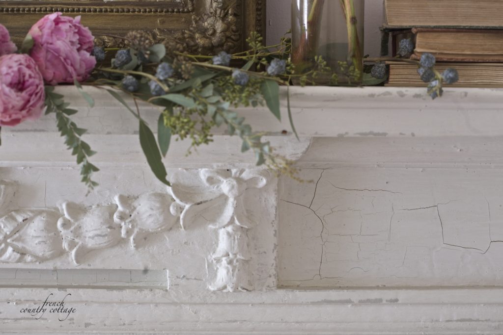 Antique fireplace mantel with peonies and greens