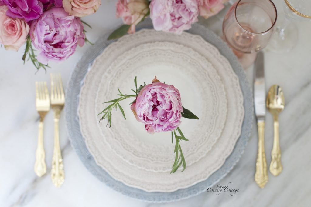 Lace dishes with peonies and gold flatware on marble 