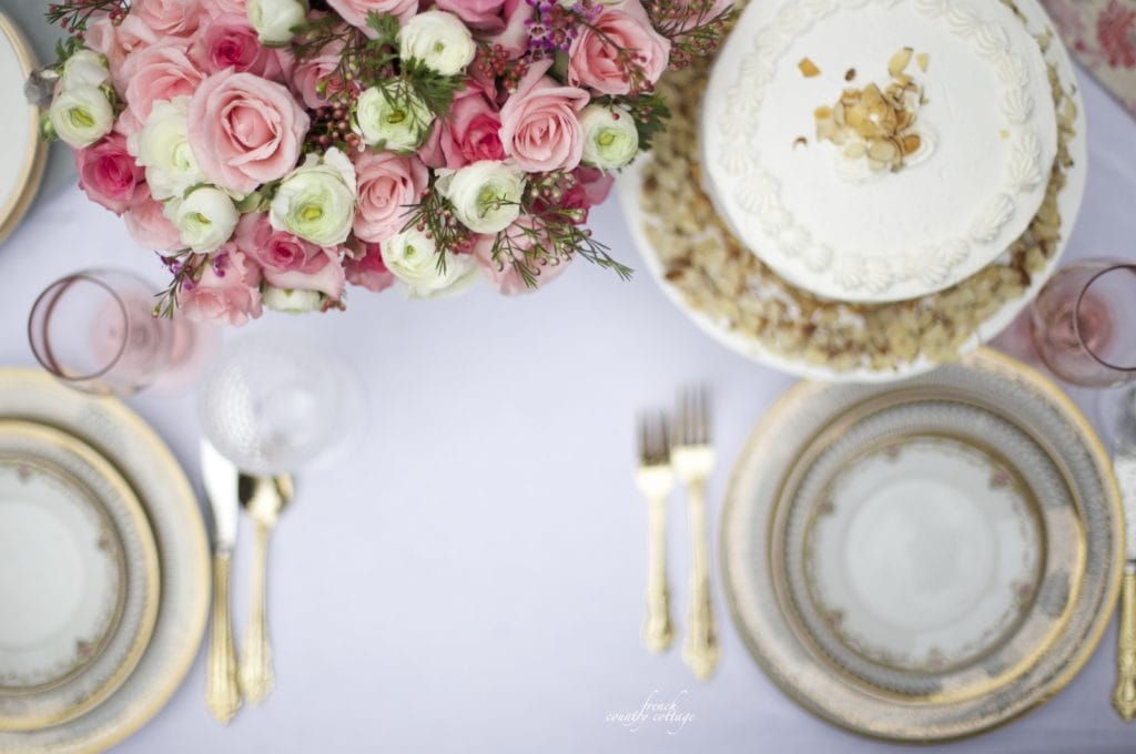 Table with gold dishes, cake and pink flowers