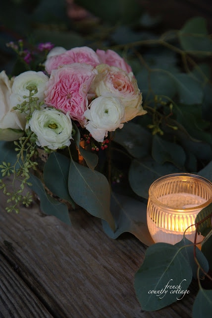Candle and roses on table top with eucalyptus garland