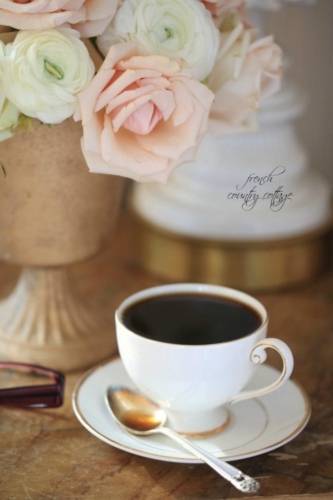 A cup of coffee on the nightstand with flowers