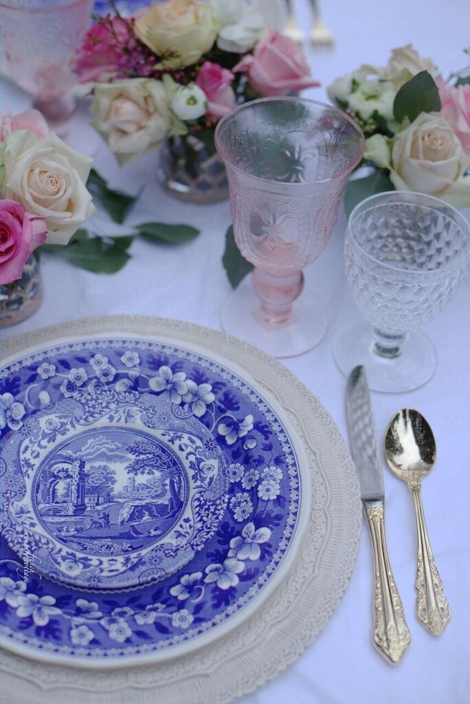 Blue and white dishes with gold flatware and pink wine stems