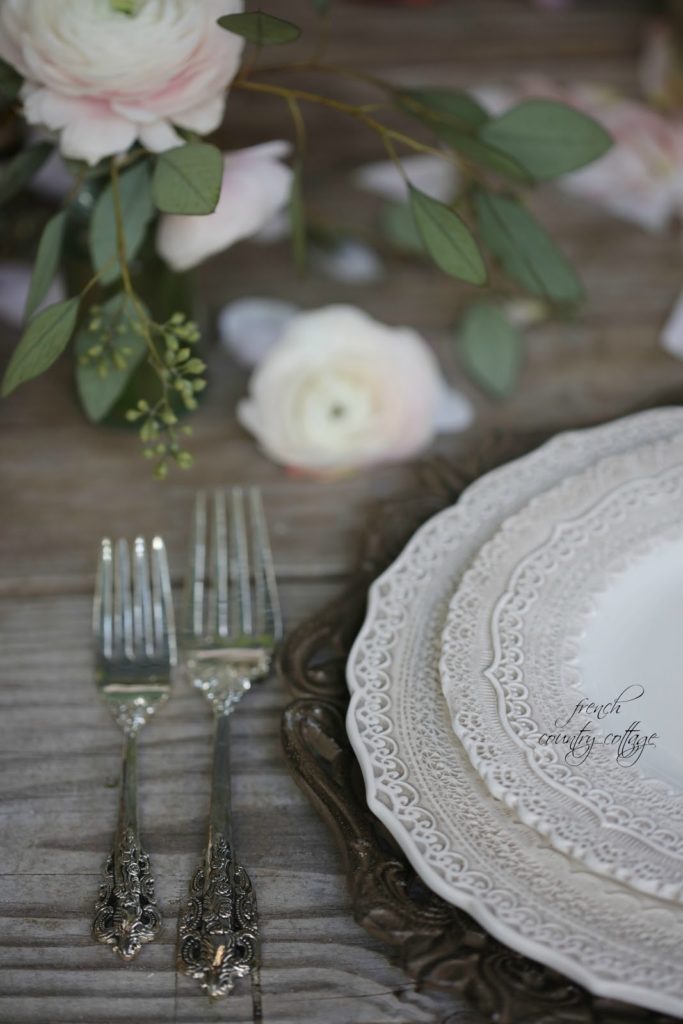Lace dishes on weathered table with silver flatware