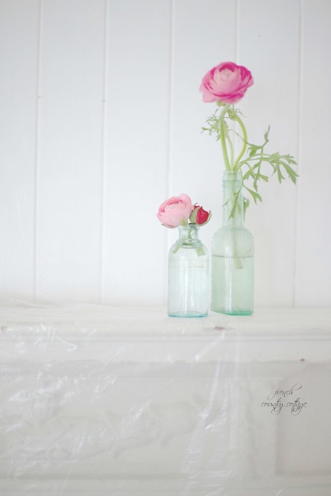 Ranunculus in jars with white paint on wood walls