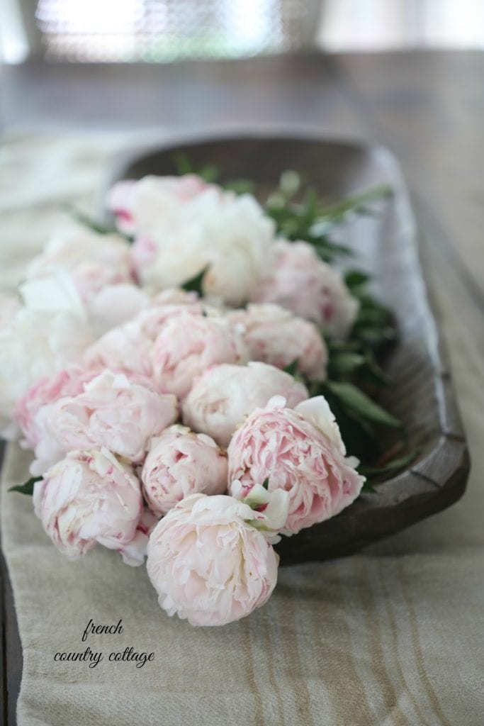 dough bowl on table with peonies and grainsack