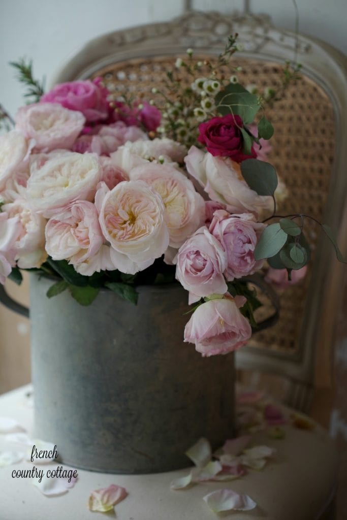 Antique zinc bucket filled with garden roses on chair