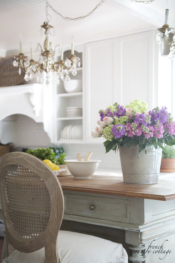 french cottage style kitchen island with a bucket of flowers
