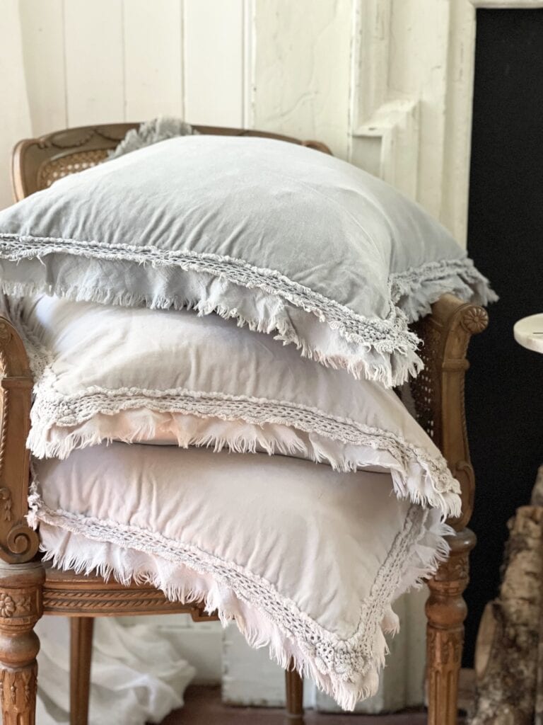 stack of velvet pillows on chair in bedroom 